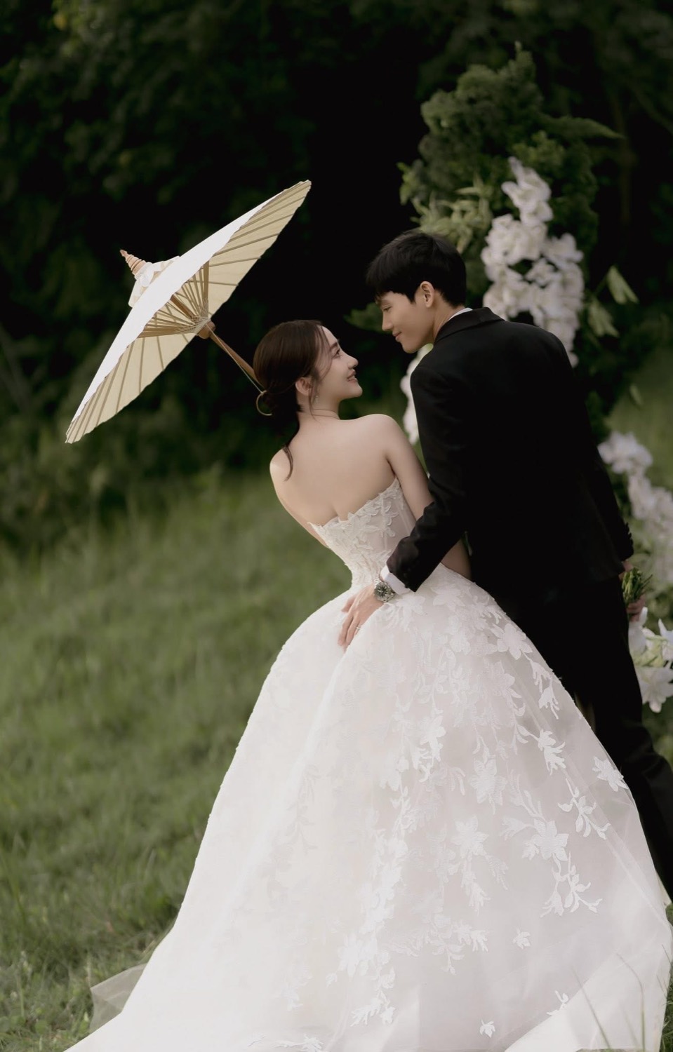 Bride and groom under a paper parasol among white florals