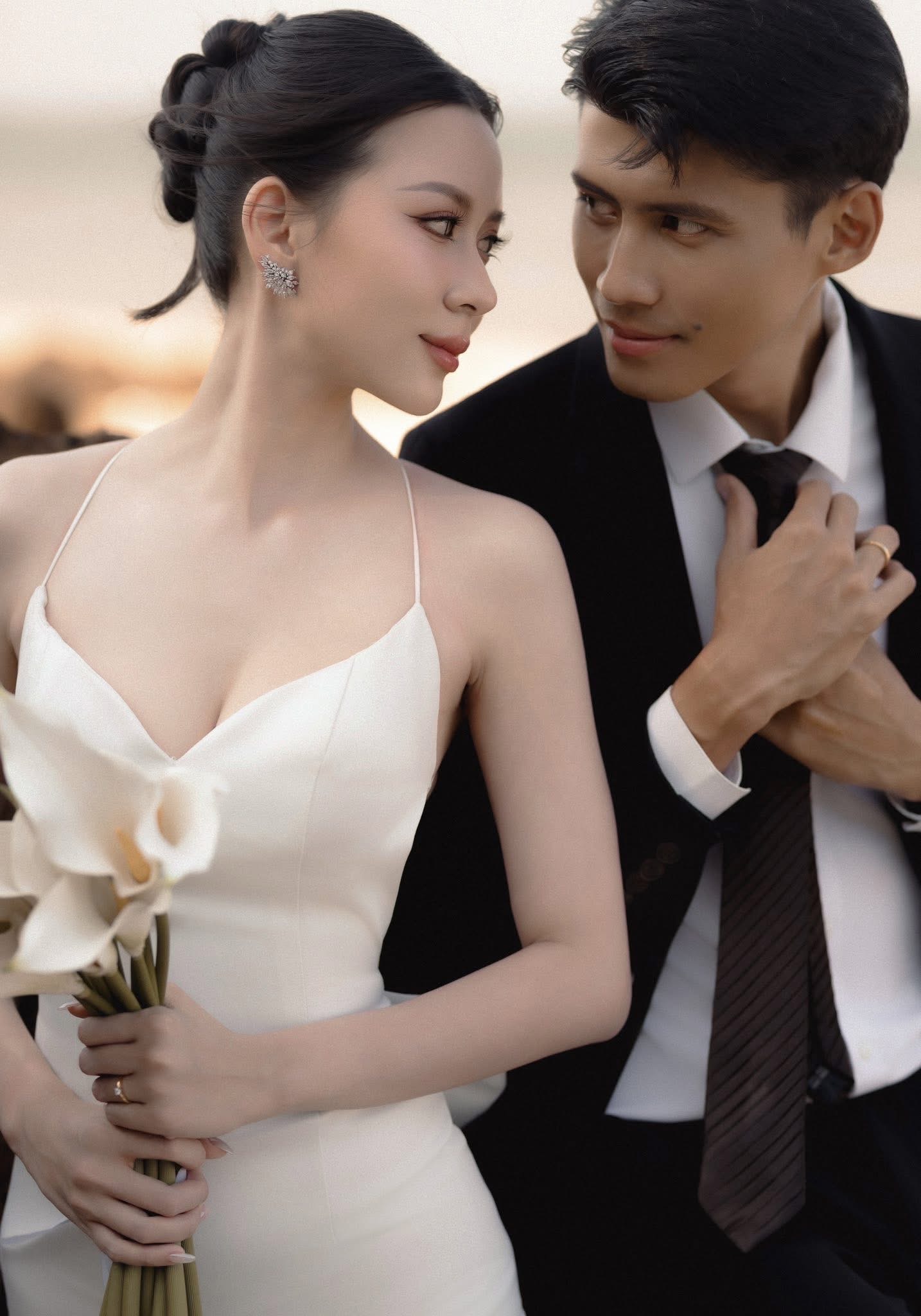 Bride holding a calla lily, hair and makeup by the studio's owner, her groom beside her