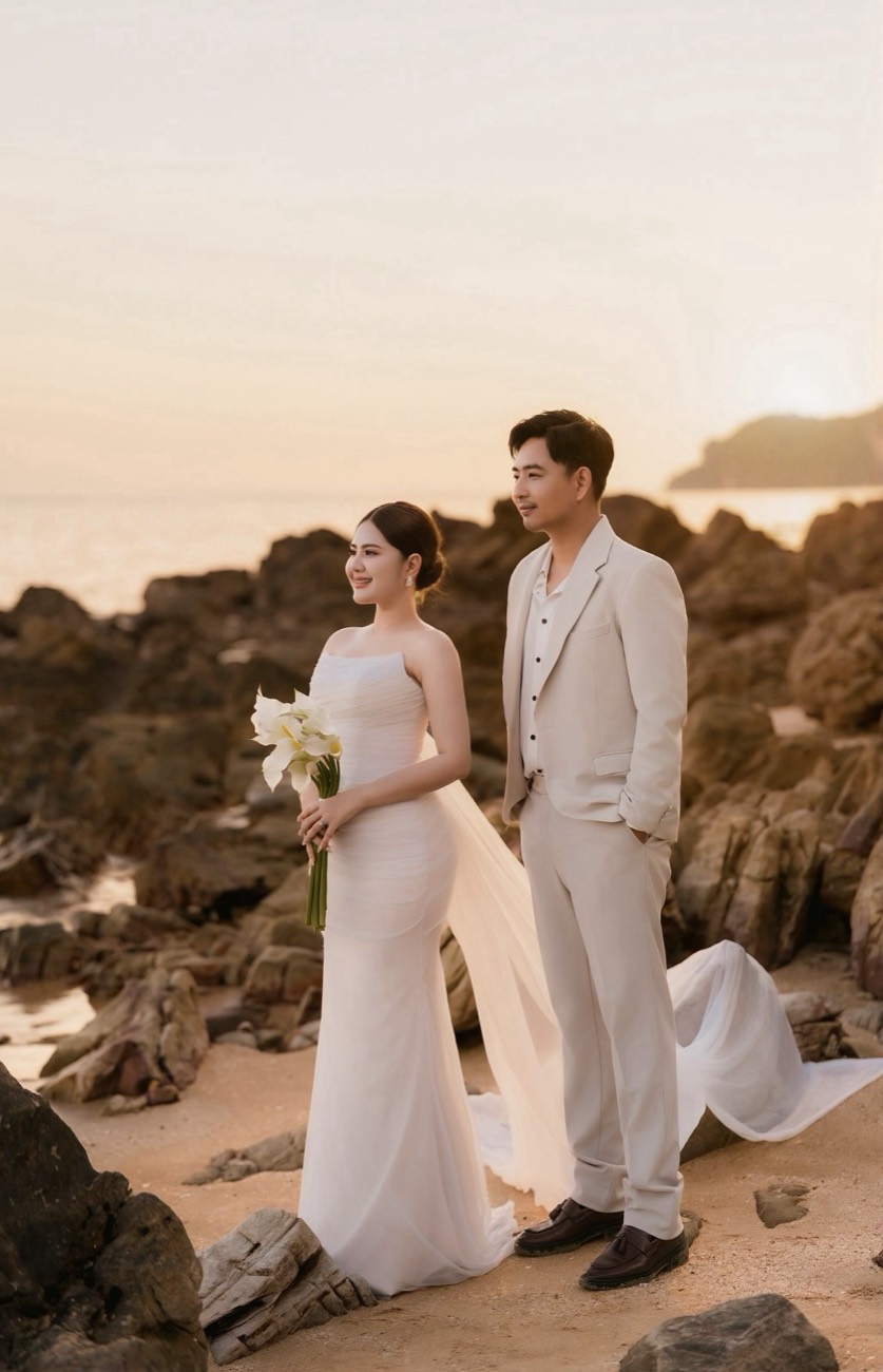 Bride holding calla lilies with her groom on the shore at golden hour